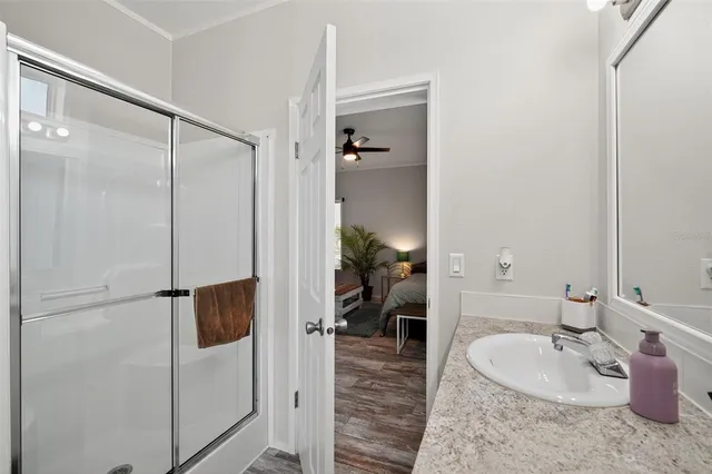 a bathroom with a granite countertop sink a mirror and shower
