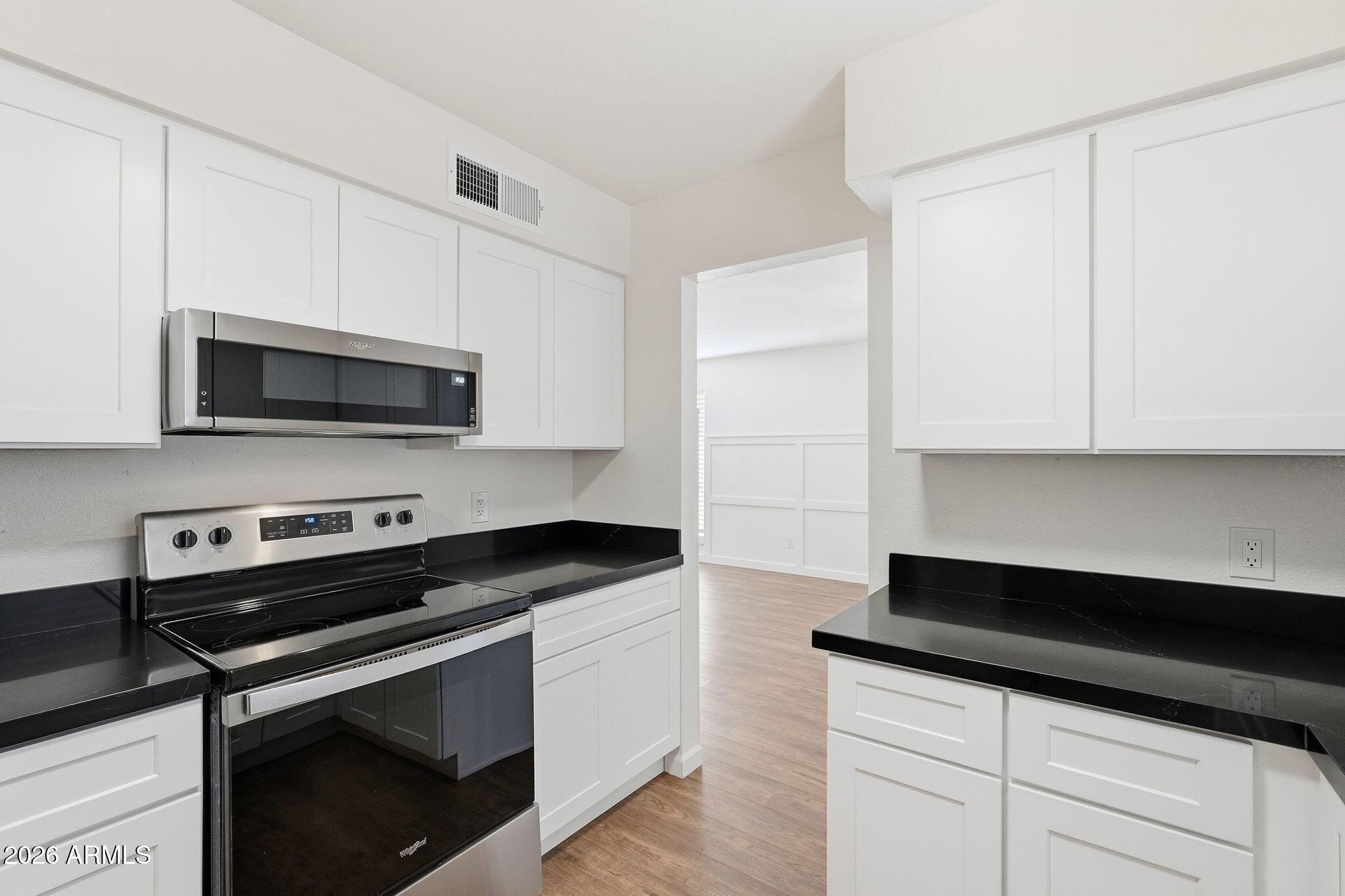 231 North Robson, Unit 7 Mesa, AZ 85201 - Photo 12 of 29 a kitchen with granite countertop white cabinets and black appliances