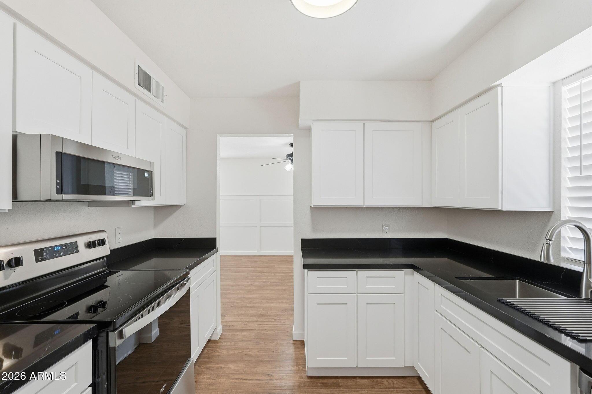 231 North Robson, Unit 7 Mesa, AZ 85201 - Photo 15 of 29 a kitchen with granite countertop white cabinets and black appliances