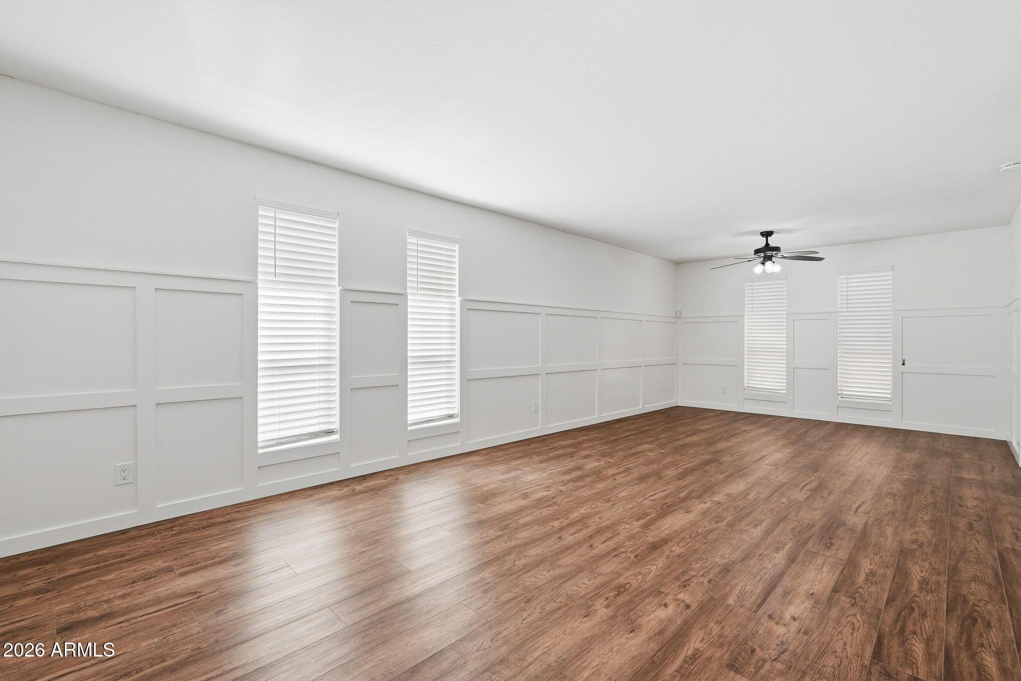231 North Robson, Unit 7 Mesa, AZ 85201 - Photo 2 of 29 an empty room with wooden floor ceiling fan and windows