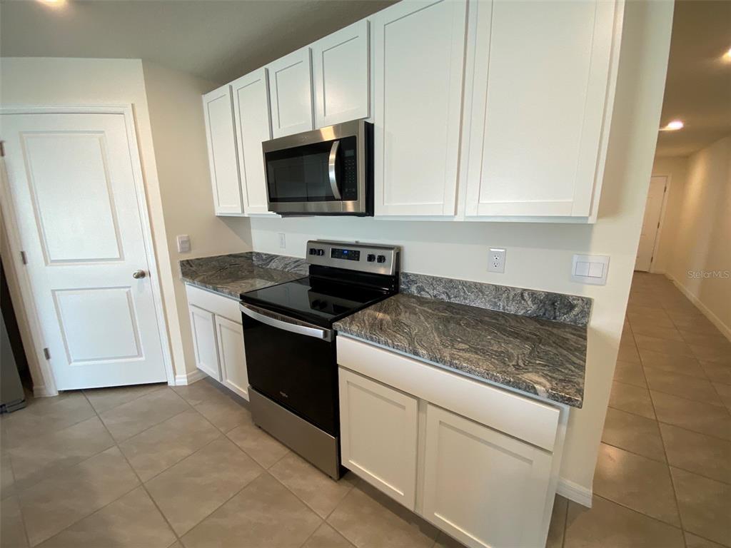 4961 Southwest 88th Place Ocala, FL 34476 - Photo 16 of 50 a kitchen with white cabinets and black appliances