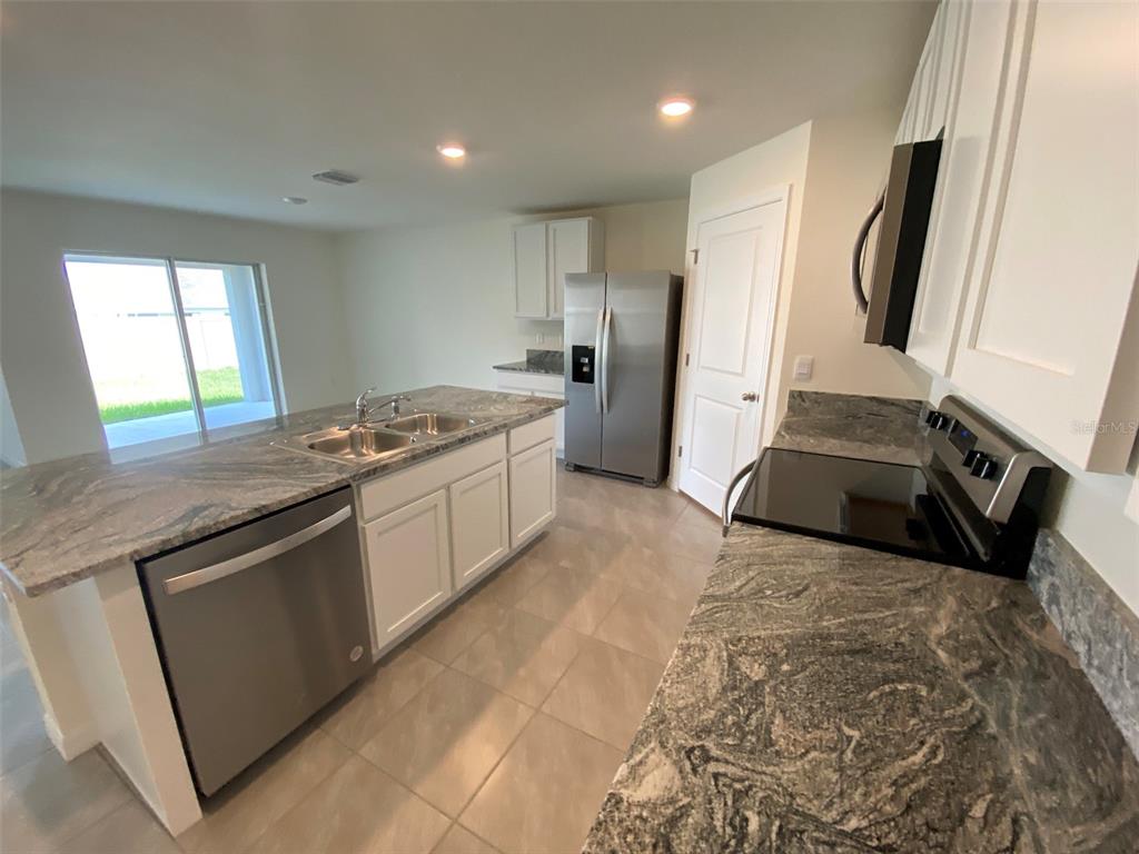 4961 Southwest 88th Place Ocala, FL 34476 - Photo 17 of 50 a kitchen with granite countertop a sink stove and refrigerator