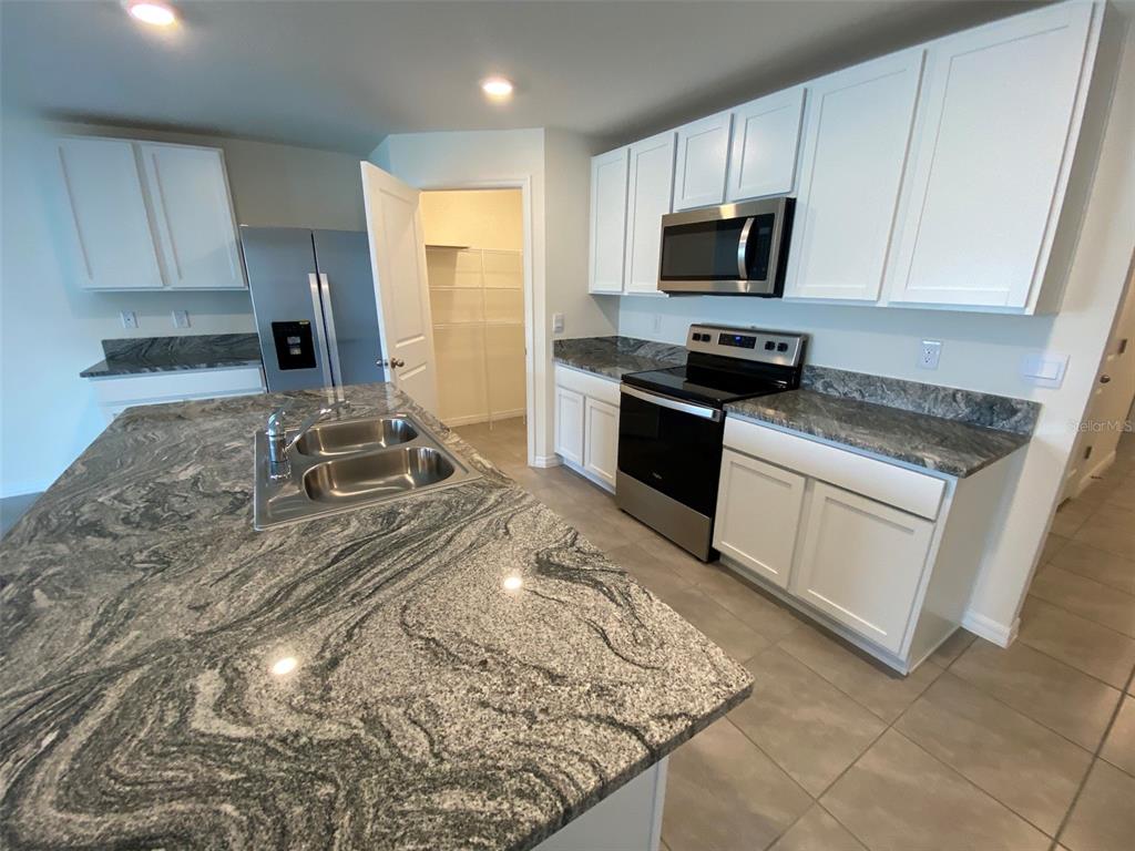 4961 Southwest 88th Place Ocala, FL 34476 - Photo 20 of 50 a kitchen with a stove a sink and a microwave