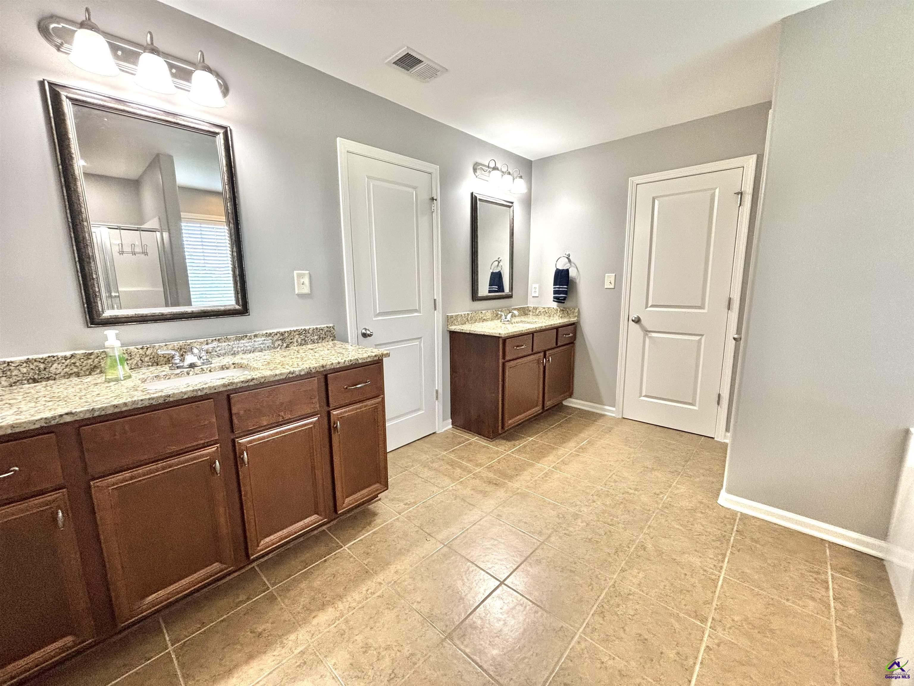 600 Post Oak Way Warner Robins, GA 31088 - Photo 32 of 50 a spacious bathroom with a granite countertop sink a mirror and a bathtub