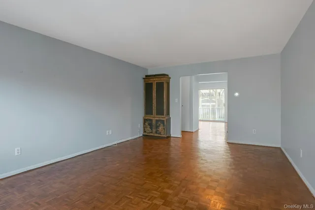 a view of an empty room with wooden floor and windows