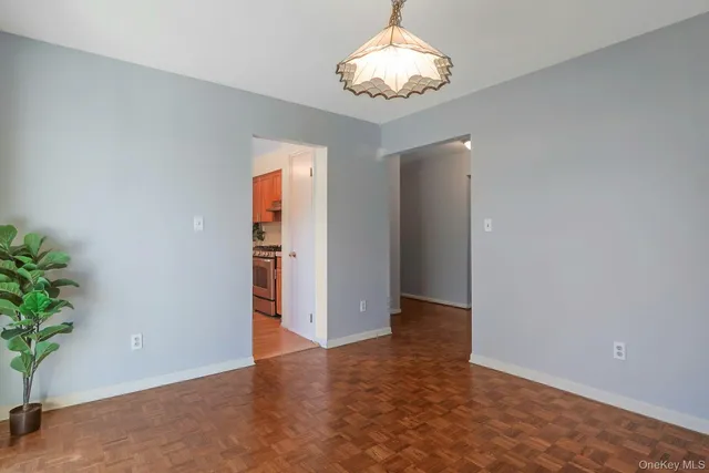 an empty room with a chandelier fan and wooden floor