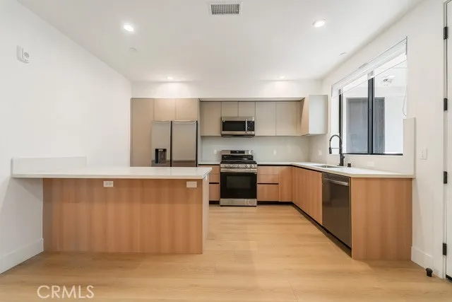 a large kitchen with stainless steel appliances wooden cabinets and a counter top space