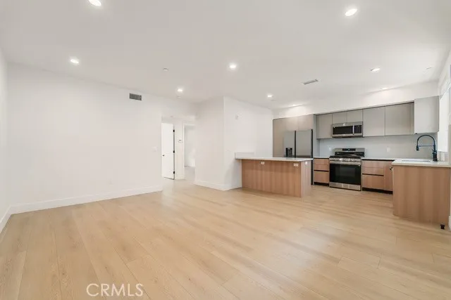 a large kitchen with stainless steel appliances a large counter top a stove and a refrigerator