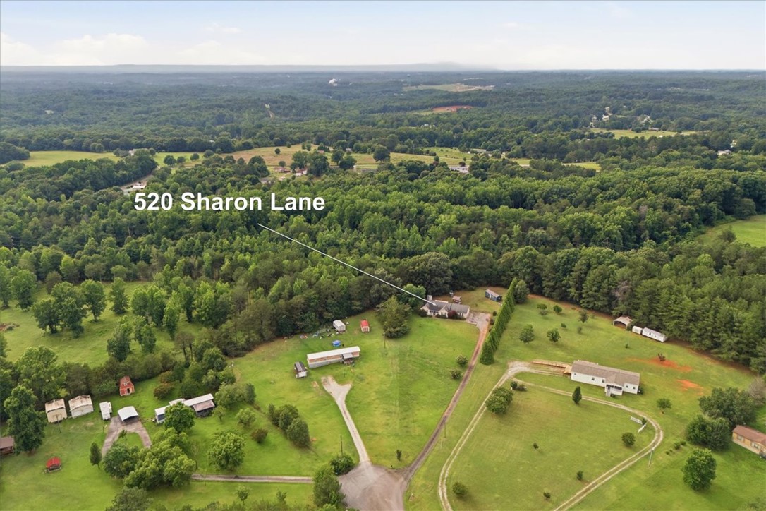 520 Sharon Lane Seneca, SC 29678 - Photo 5 of 48 An aerial panorama reveals an expansive green lot with several structures and a dense wooded perimeter.