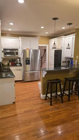 a kitchen with stainless steel appliances kitchen island granite countertop a table chairs and a refrigerator