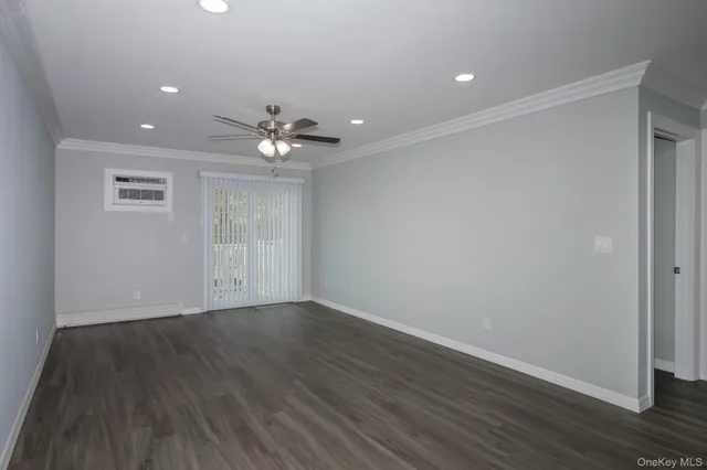 a view of an empty room with wooden floor and a ceiling fan