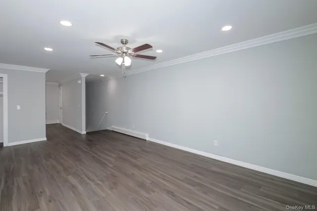 an empty room with wooden floor and a ceiling fan