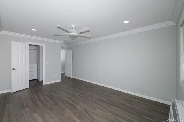 an empty room with wooden floor and a ceiling fan