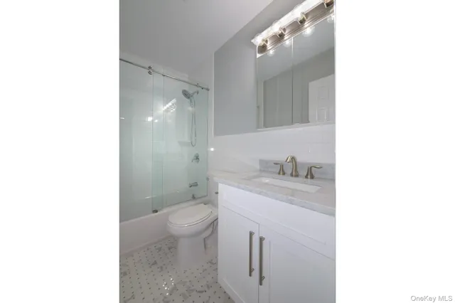 a bathroom with a granite countertop sink a toilet and a mirror