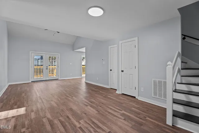 an empty room with wooden floor chandelier fan and windows
