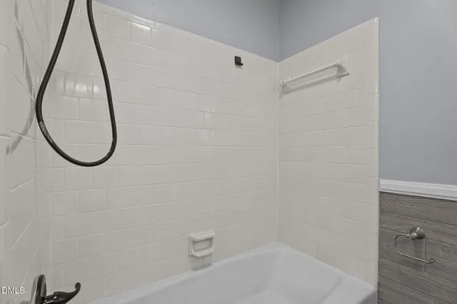 a bathroom with a tub a mirror and a shower
