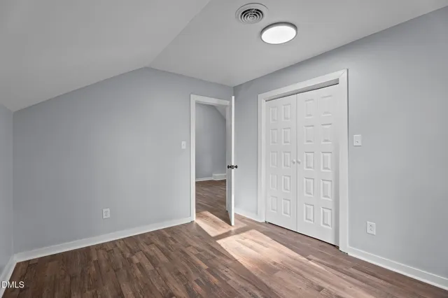 an empty room with wooden floor and window