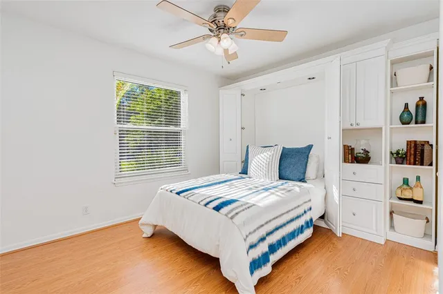 a view of a bedroom with cabinet a ceiling fan and windows
