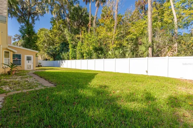 a view of a house with a big yard and large trees