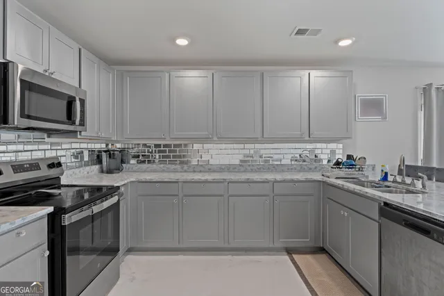 a kitchen with stainless steel appliances kitchen island granite countertop a refrigerator and a stove top oven