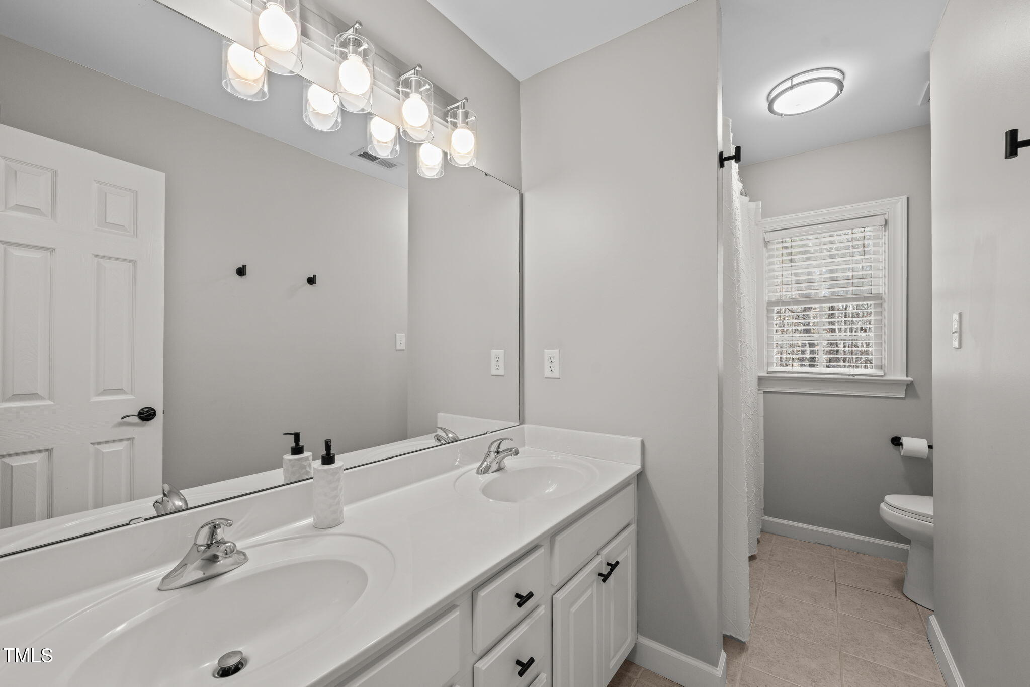 5032 Big Creek Road Raleigh, NC 27613 - Photo 29 of 46 a bathroom with double vanity sink a toilet and a mirror