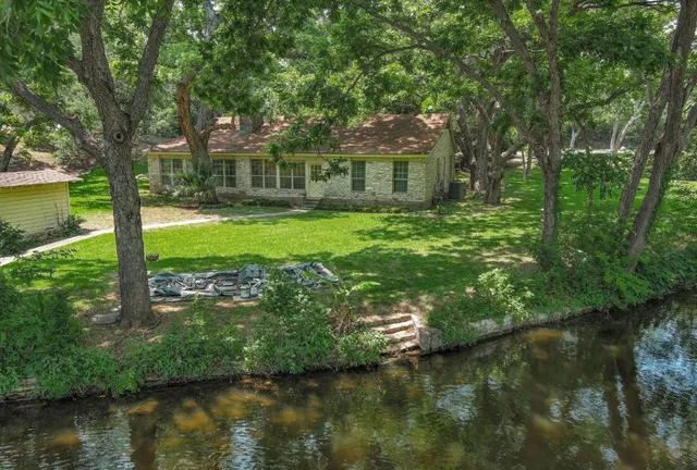 a view of a house with a yard and a large tree