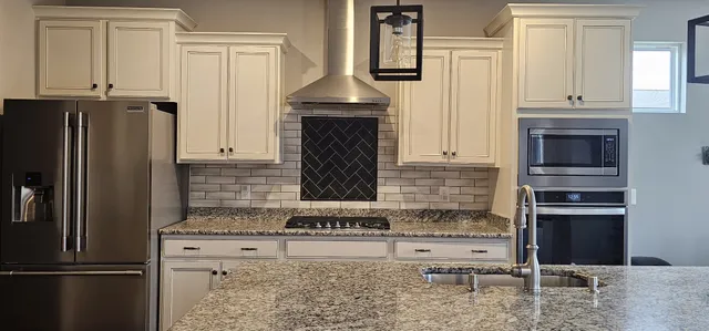 a kitchen with granite countertop a refrigerator stove and cabinets
