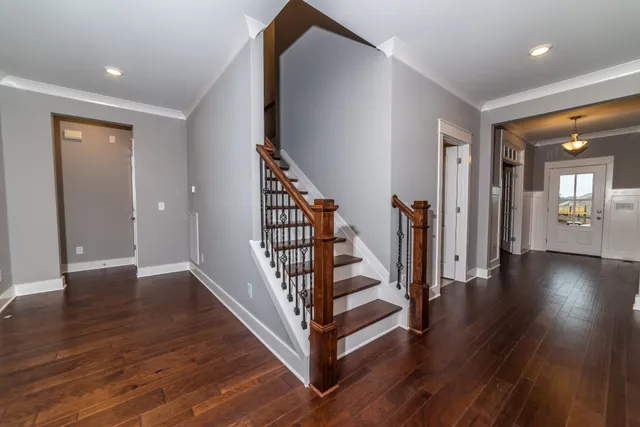 a view of a hallway with wooden floor and stairs