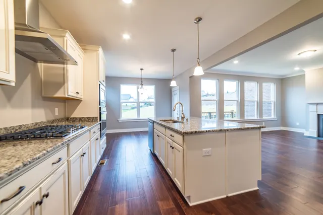 a kitchen with granite countertop a stove a sink wooden floor and a large window