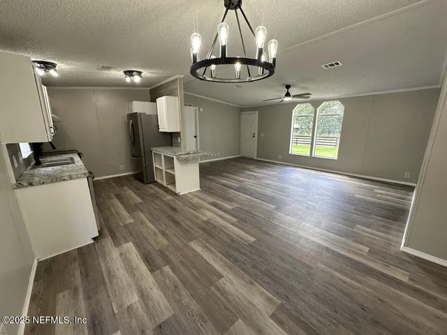 a view of a kitchen and an empty room with wooden floor