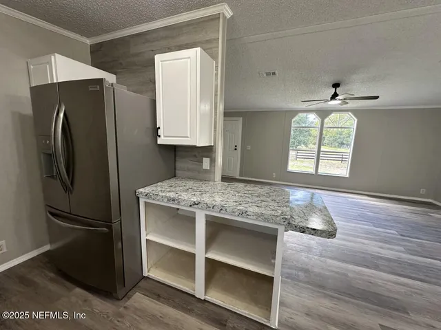 a kitchen with granite countertop a refrigerator and a stove top oven