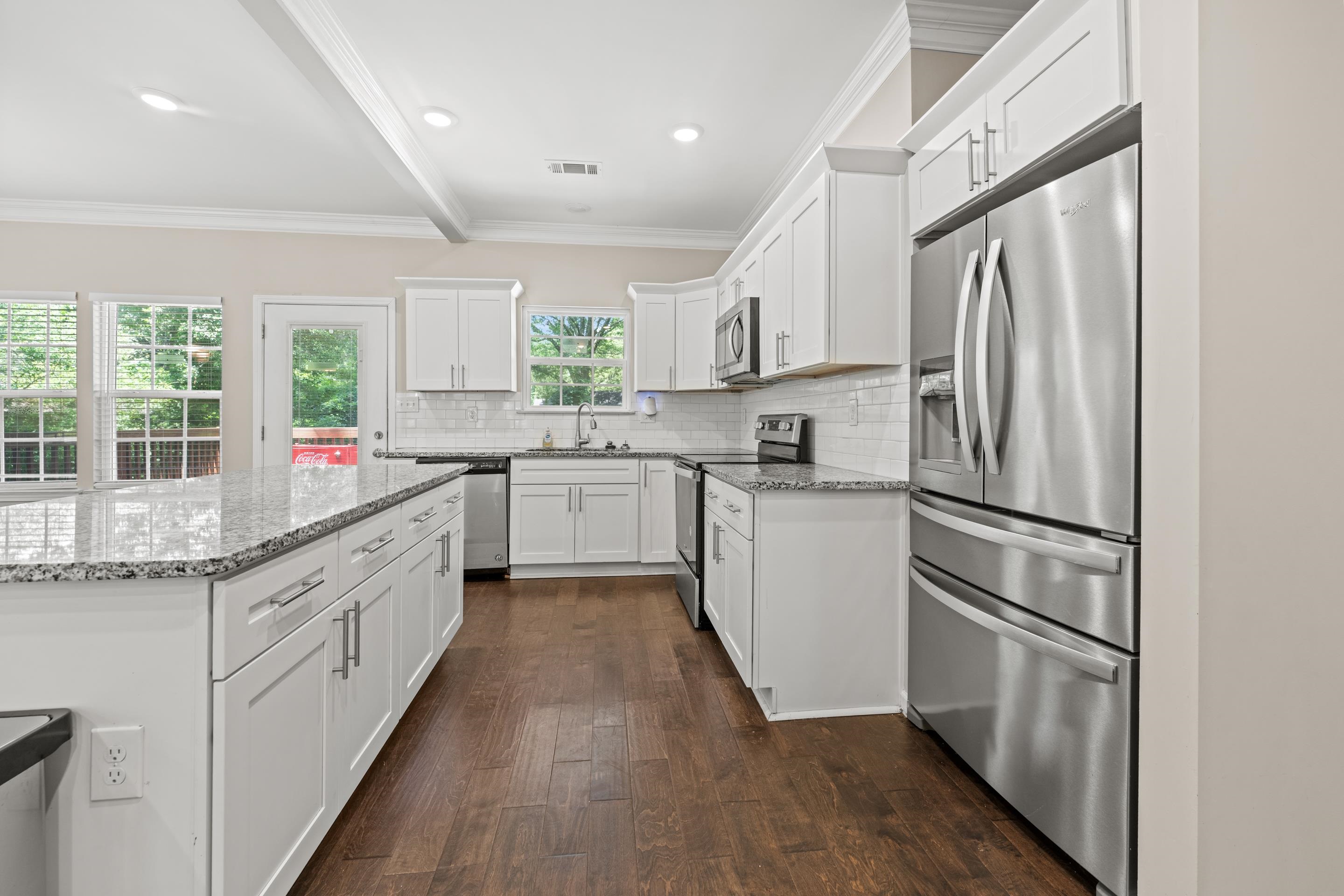 1255 Colonial Road Memphis, TN 38117 - Photo 11 of 30 Contemporary kitchen with white shaker cabinetry, stainless steel appliances, speckled stone countertops, and wood-finish flooring