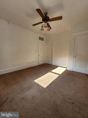 an empty room with a ceiling fan and window