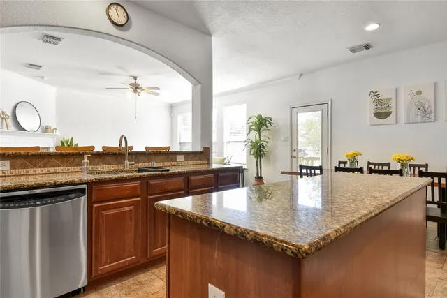 a kitchen with granite countertop a sink a counter top space and living room view
