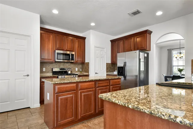 a kitchen with stainless steel appliances granite countertop a stove refrigerator sink and microwave