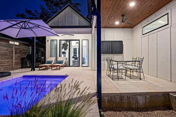 a patio with table and chairs and potted plants