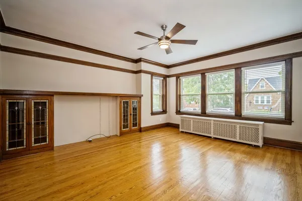 a view of an empty room with window and wooden floor