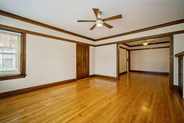 a view of an empty room with wooden floor and a window