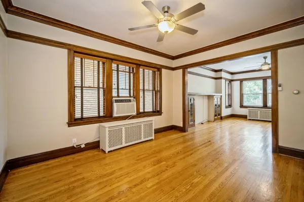 a view of an empty room with window and wooden floor
