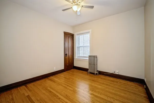 an empty room with wooden floor chandelier fan and windows
