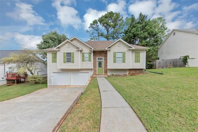 a front view of a house with a yard and trees