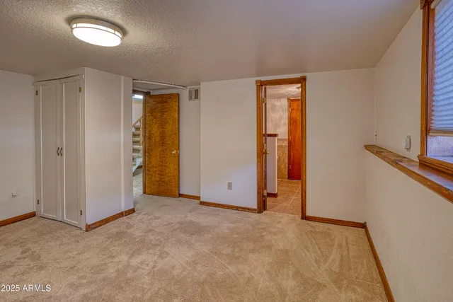 an empty room with chandelier fan and windows
