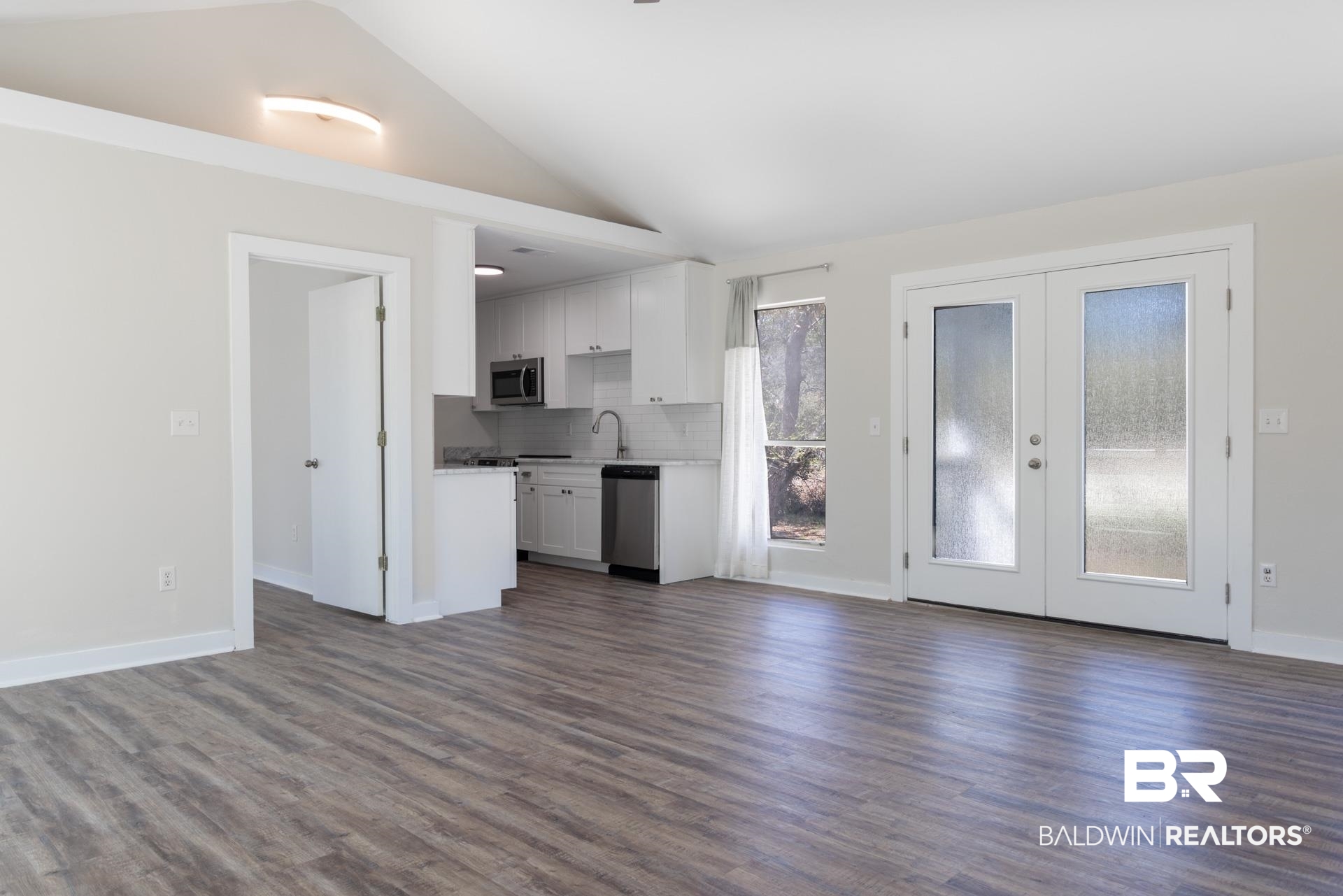413 West Fort Morgan Road Gulf Shores, AL 36542 - Photo 5 of 29 Unfurnished living room featuring baseboards, dark wood finished floors, lofted ceiling, french doors, and a sink