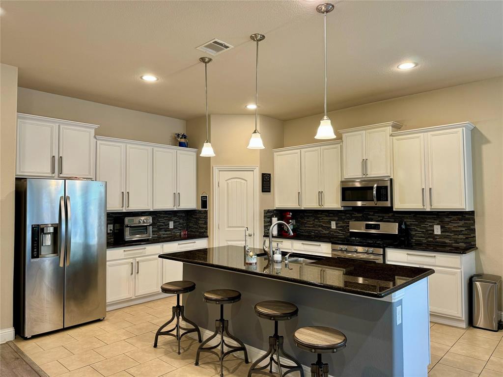 a kitchen with granite countertop a sink a counter space appliances and cabinets
