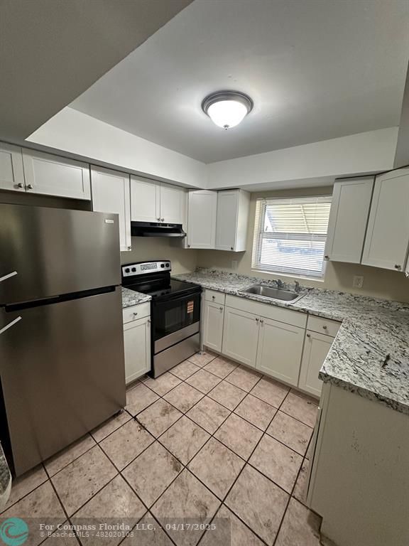 1350 East Sample Road, Unit 101 Pompano Beach, FL 33064 - Photo 3 of 8 a kitchen with stainless steel appliances granite countertop a refrigerator sink and cabinets