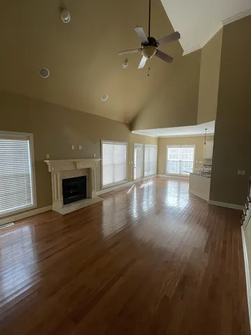 an empty room with wooden floor fireplace and a window