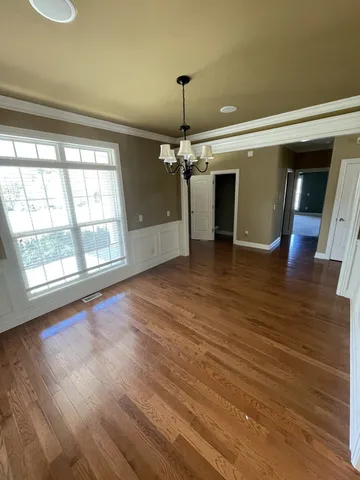 a view of a livingroom with wooden floor a ceiling fan and windows