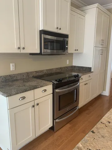 a kitchen with granite countertop white cabinets and appliances