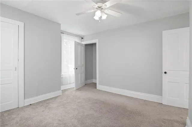 a view of an empty room and chandelier fan