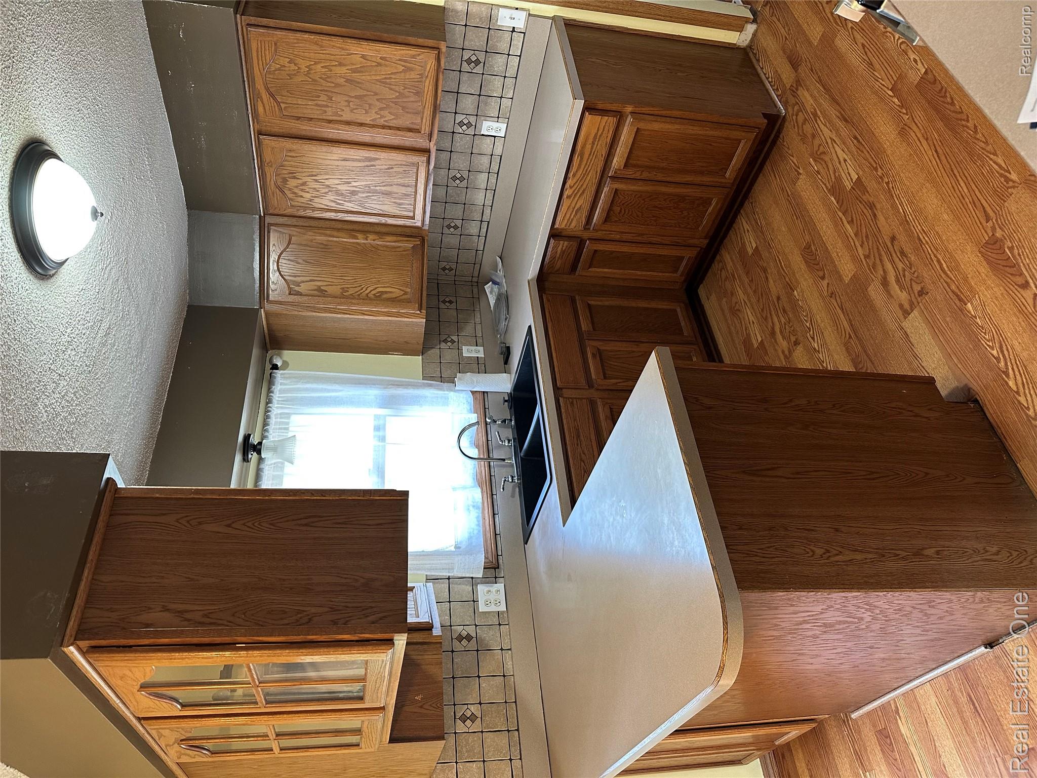 2430 Coolidge Road Barryton, MI 49305 - Photo 20 of 29 Wood-finish flooring, L-shaped countertop, double basin sink, and wood cabinetry